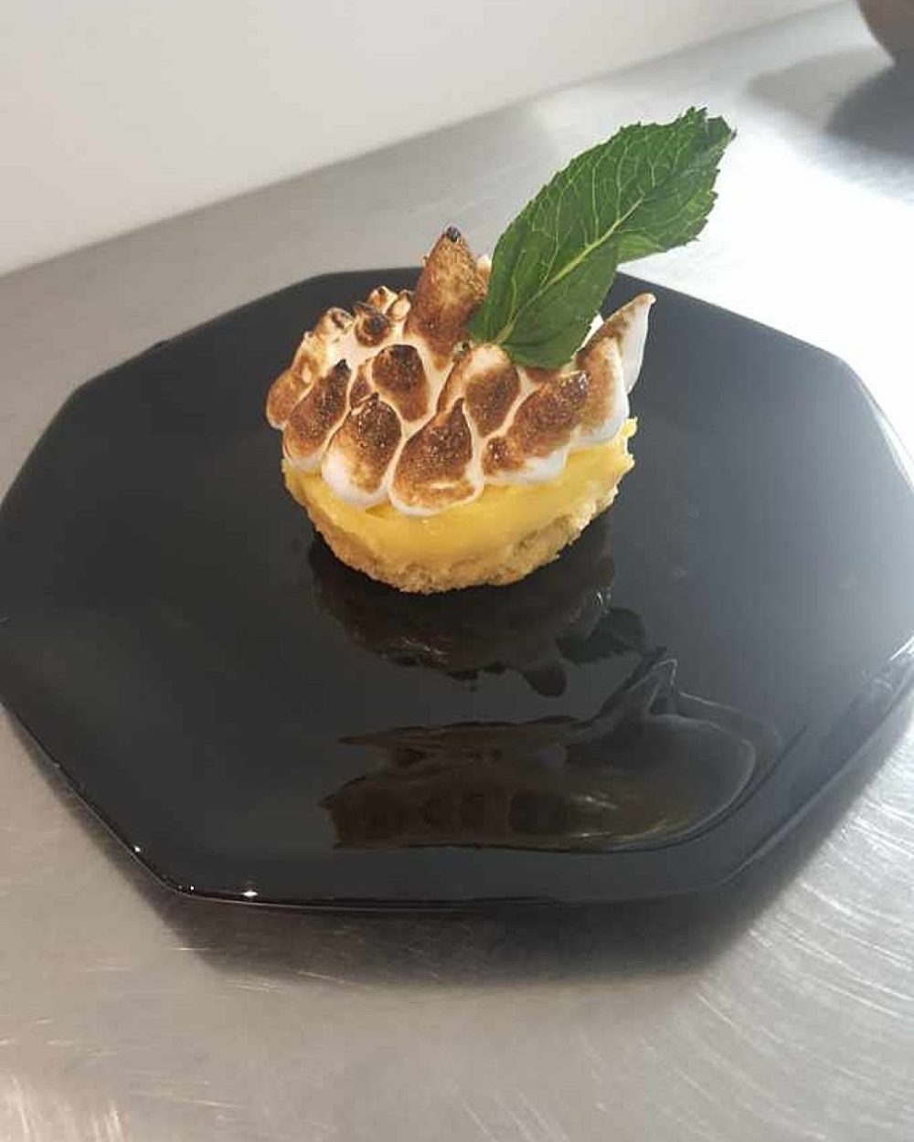 Un dessert au citron meringué, garni d'une feuille de menthe